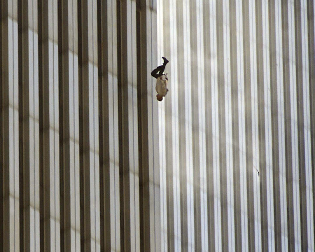 A person falls with a skyscraper in the background