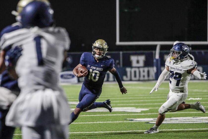 Bellflower, CA, Saturday March 13, 2021 - St. John Bosco quarterback Pierce Clarkson outraces Sierra Canyon linebacker Angelo Pulido for en route to a first half touchdown at Panish Family Stadium. (Robert Gauthier/Los Angeles Times)