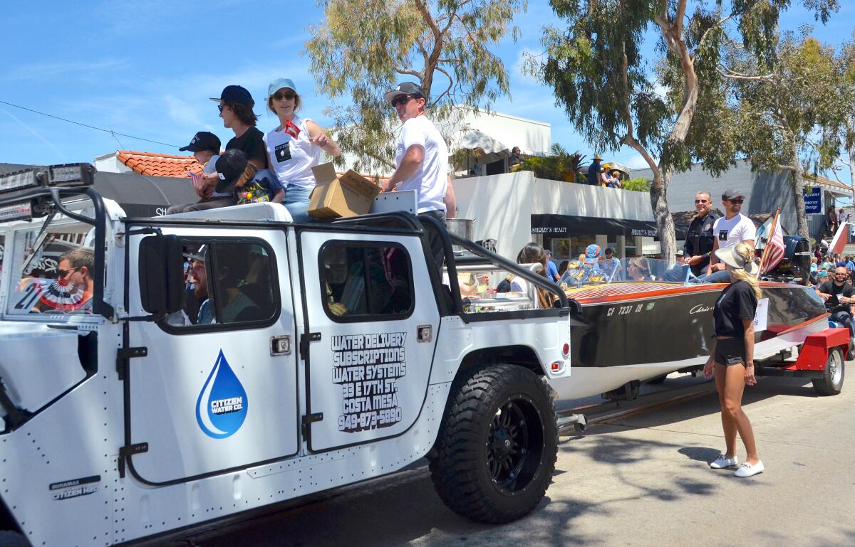 Citizen Water Co.'s Evan Krisher passes out candy while towing Newport Beach Police Chief Jon Lewis.
