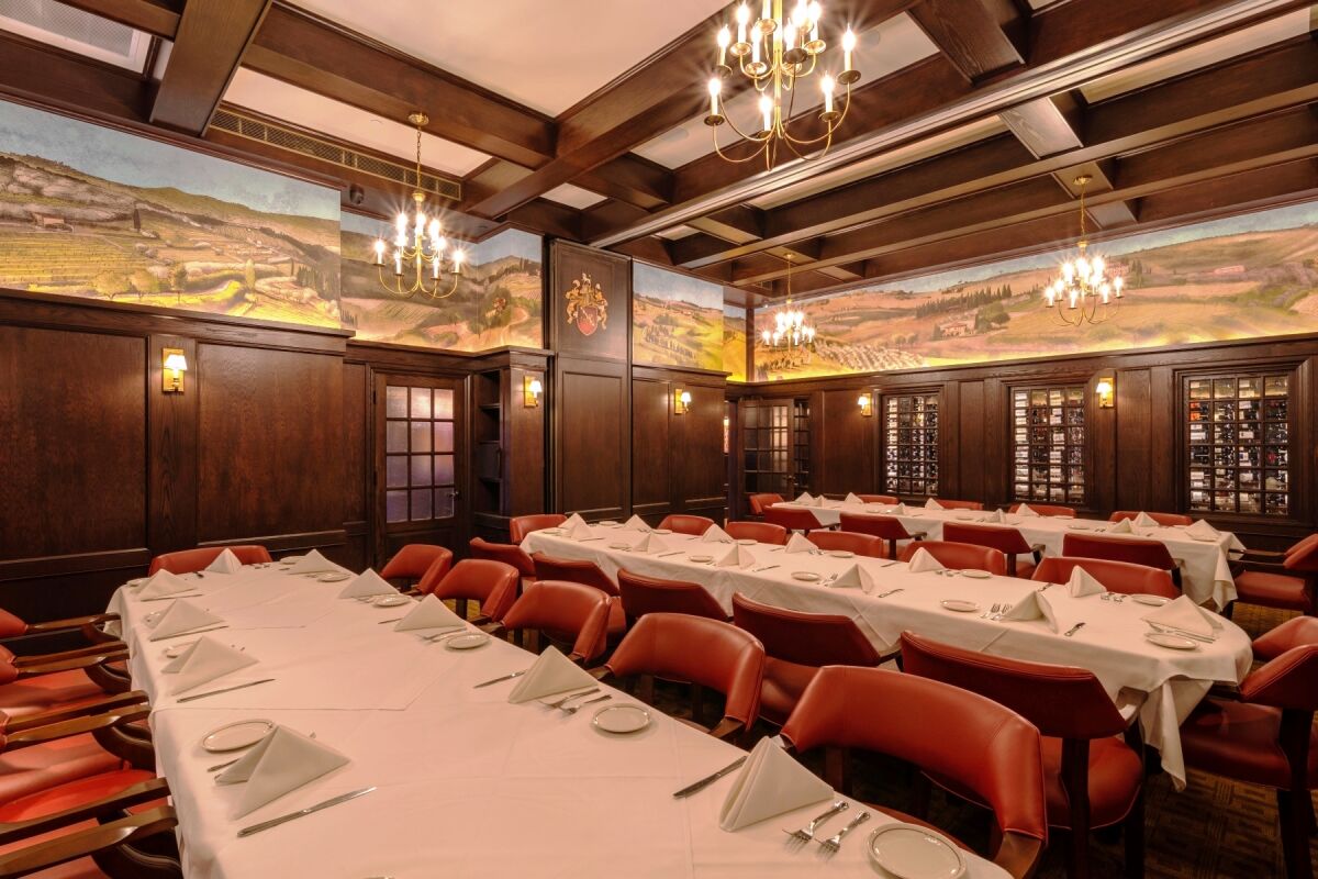 A wood-paneled dining room with murals and three long tables with chairs