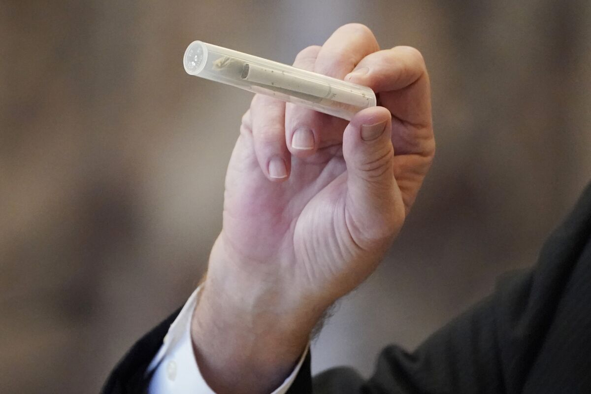State Sen. Kevin Blackwell, R-Southaven, lead negotiator, holds a tube containing a cigarette and a rolled hemp cigarette to illustrate to lawmakers what specific portions of the Mississippi Medical Cannabis Equivalency Units would look like during his presentation of the Mississippi Medical Cannabis Act in the Senate Chamber at the Mississippi State Capitol in Jackson, Miss., Thursday, Jan. 13, 2022. The body passed the act. (AP Photo/Rogelio V. Solis)