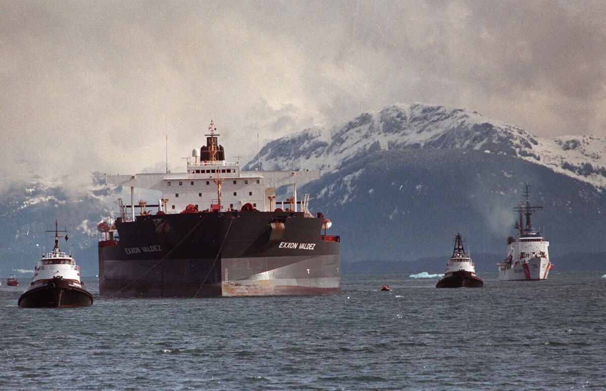 The Exxon Valdez is towed out of Prince William Sound in Alaska by a tugboat and a U.S. Coast Guard Cutter.