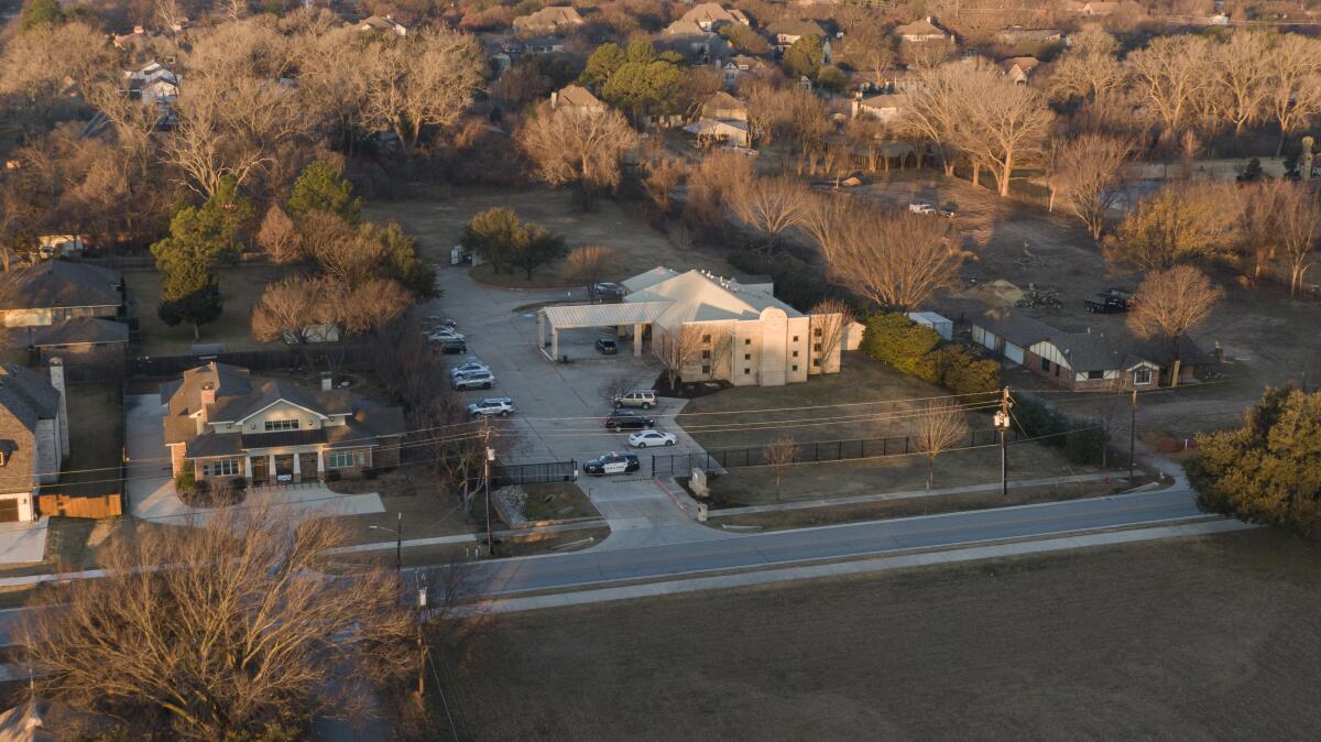 An aerial view of a synagogue with a police car blocking the entrance
