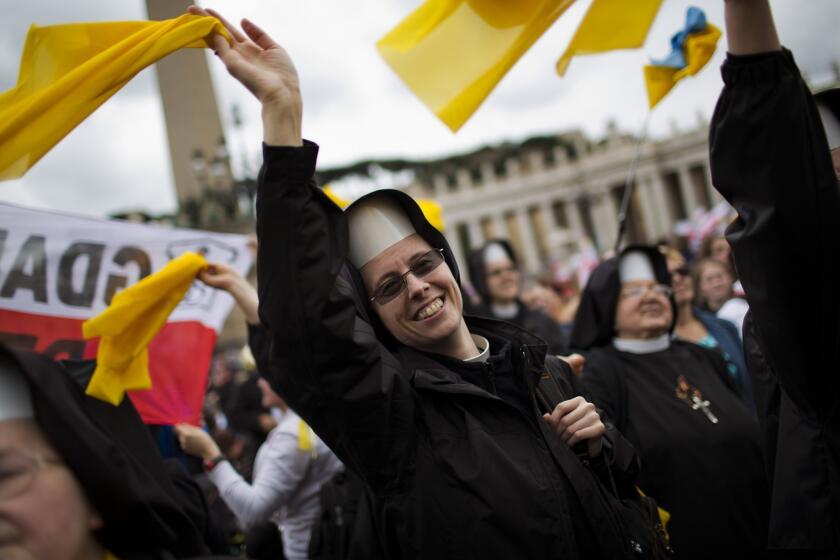Nuns wave as Pope Francis is driven through the crowd after presiding over the canonization ceremony in St. Peter's Square.