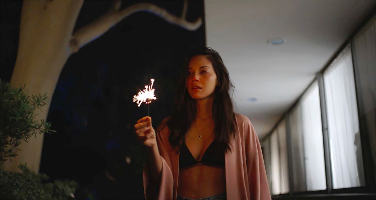 A woman holds a sparkler in the 2021 drama “Violet.”