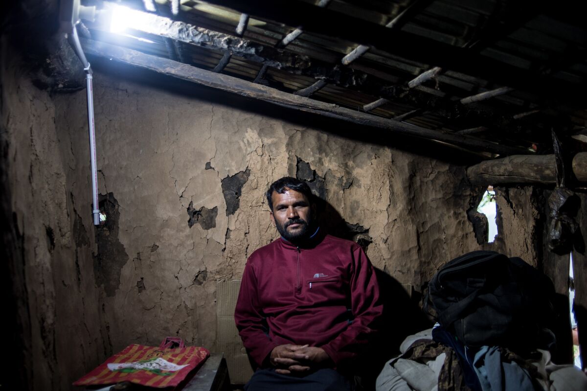 Ashtmohan Chauhan stands under an electric bulb after his house in Barnali got electricity.
