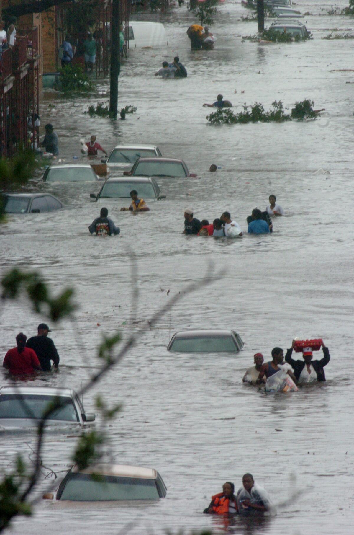 New Orleans residents move to higher ground as rising water floods a street in Orleans Parish. Hurricane Katrina delivered a hard but glancing blow to the Big Easy. (Douglas R. Clifford / Associated Press)
