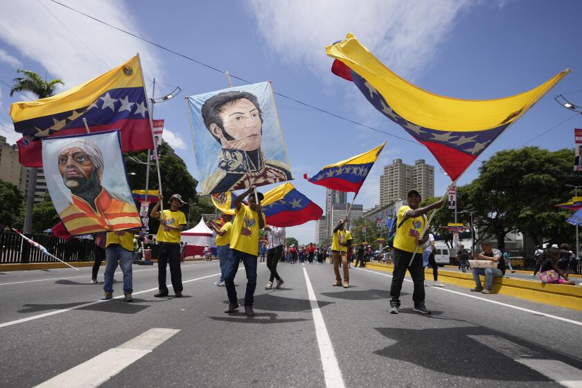 Simpatizantes del presidente venezolano, Nicolás Maduro, ondean banderas nacionales y carteles con las imágenes de héroes nacionales a su llegada para el acto de cierre de campaña de Maduro en Caracas, Venezuela, el jueves 25 de julio de 2024. Venezuela va a elecciones presidenciales el domingo 28 de julio. (AP Foto/Fernando Vergara)