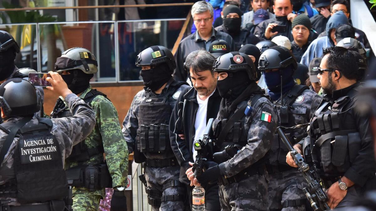 Agents of the Criminal Investigation Agency and Mexican soldiers escort Damaso Lopez, senior lieutenant of jailed drug lord Joaquin "El Chapo" Guzman, after arresting him May 2, 2017, in Mexico City.