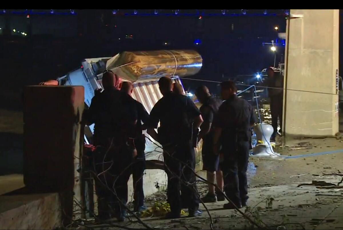 Police officers watch as an overturned pontoon boat is pulled from the Ohio River.