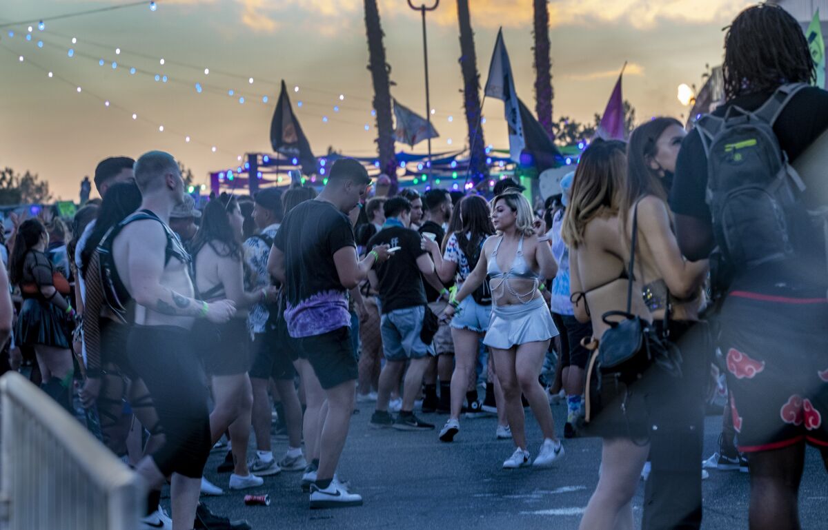 Non-masked festival-goers stand under strings of lights
