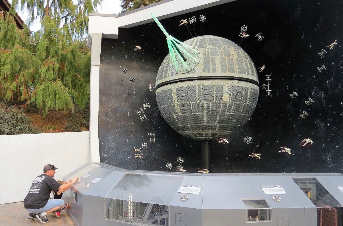 A father and daughter push automation buttons for the Death Star model, made from 500,000 Lego bricks, in the Star Wars Miniland attraction at Legoland California theme park in Carlsbad on Nov. 18. The Star Wars attraction will close for good on Jan. 6.