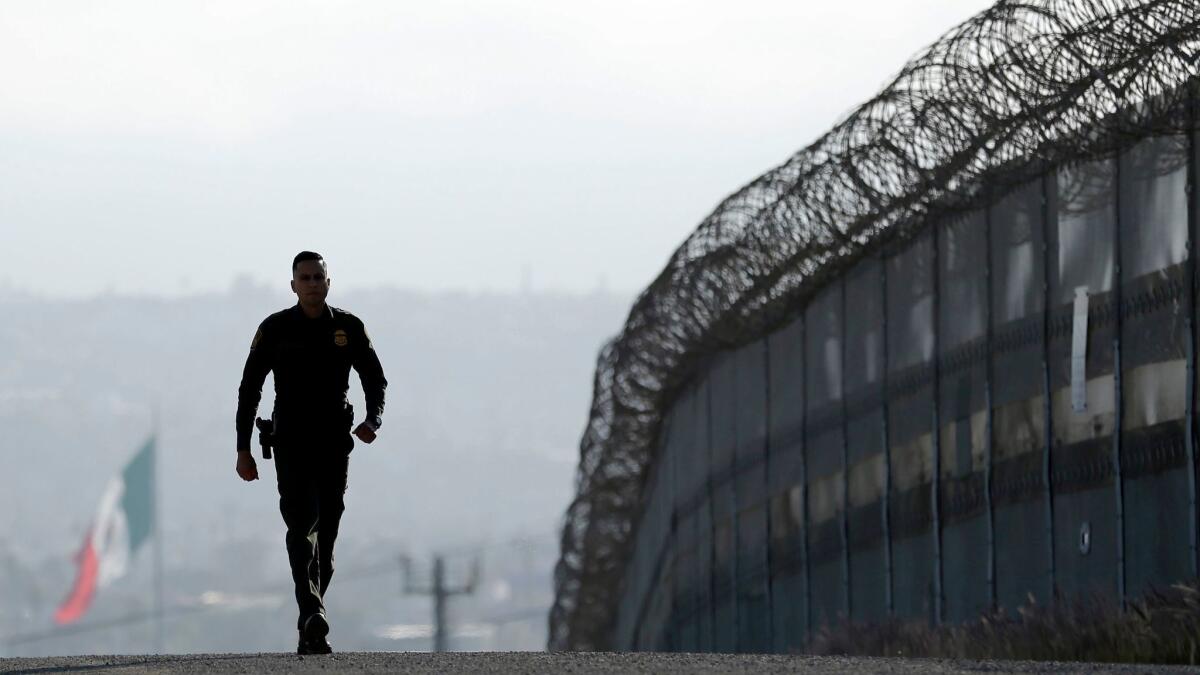 Border Patrol agent Eduardo Olmos walks near the secondary fence separating Tijuana, Mexico, from San Diego in 2016.