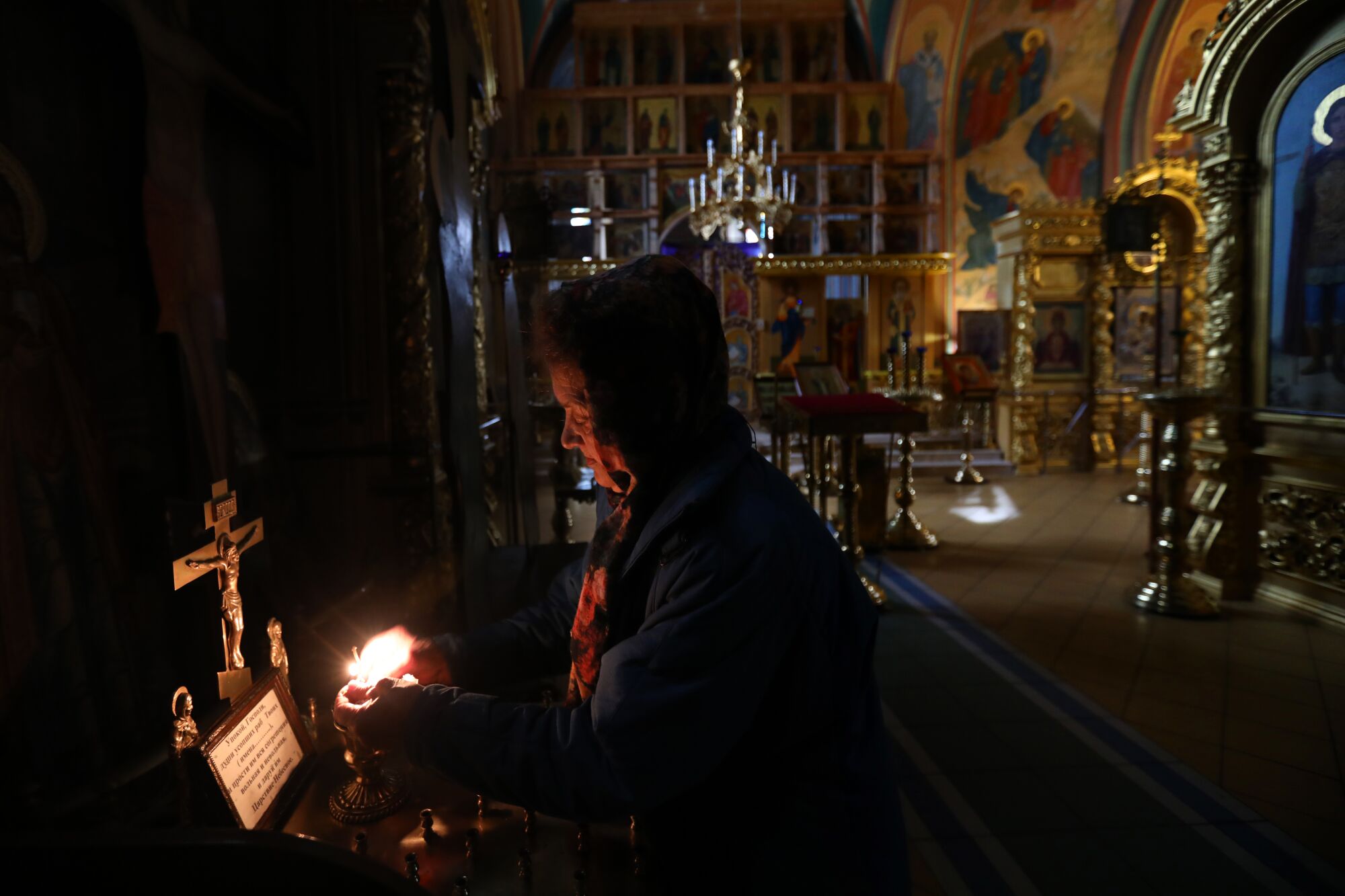 Woman lights candles in a cathedral.