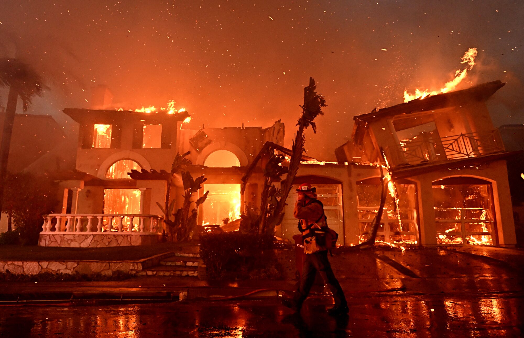 A firefighter walks past burning homes