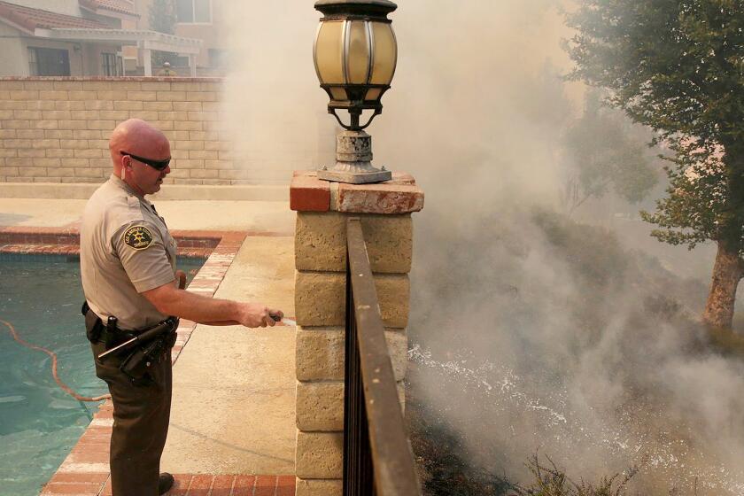 A march 2017 photo of L.A. County Sheriff's Deputy Jason Viger hosing down a hot spot in Newhall.