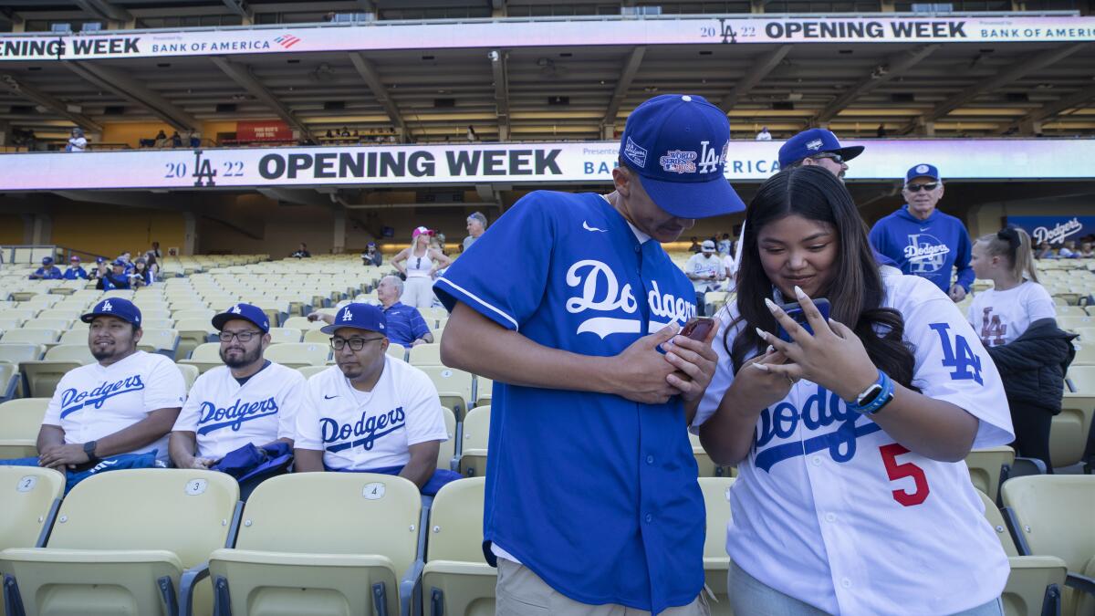 Dodgers fans Jacob Solis, left, and Selena Zuniga try to get pictures of players.