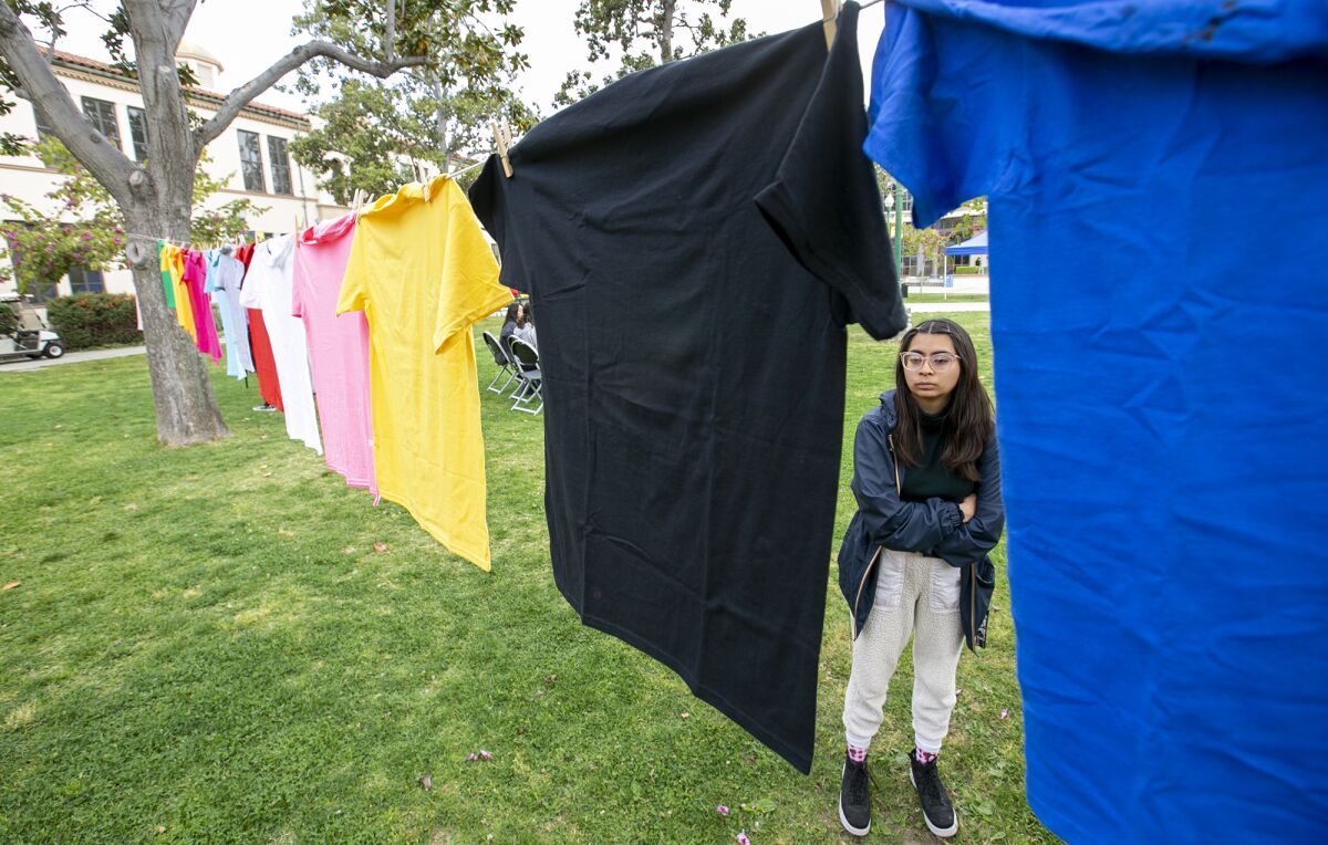 Wendy Medina reads T-shirts that tell stories of sexual assault from the Waymakers' Clothesline Project.