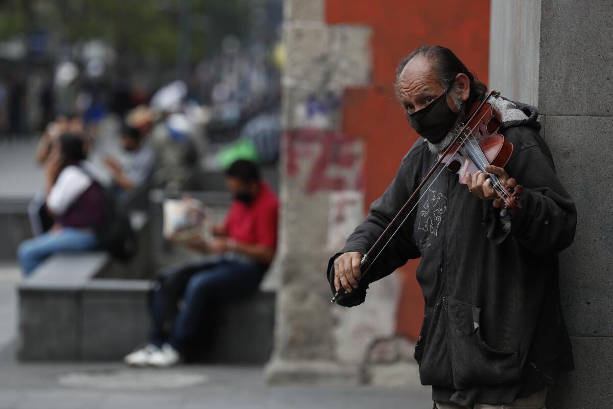 Fernando Castro, de 59 años, toca el violín para ganar propinas de gente que pasa caminando en Avenida Juárez en Ciudad de México el domingo 31 de mayo de 2020.