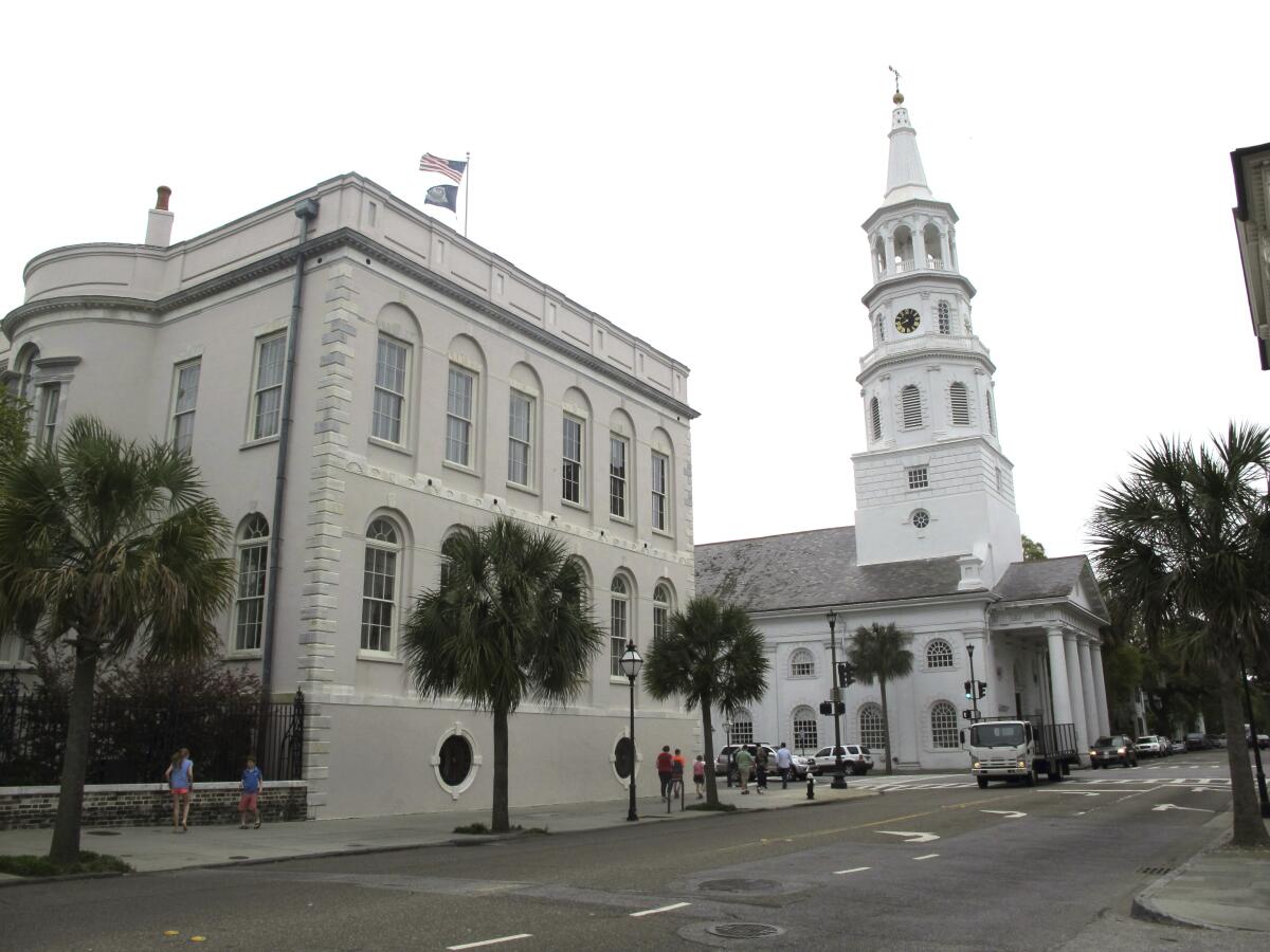 Pedestrians walk by City Hall and St. Michael's Episcopal Church in Charleston, S.C.