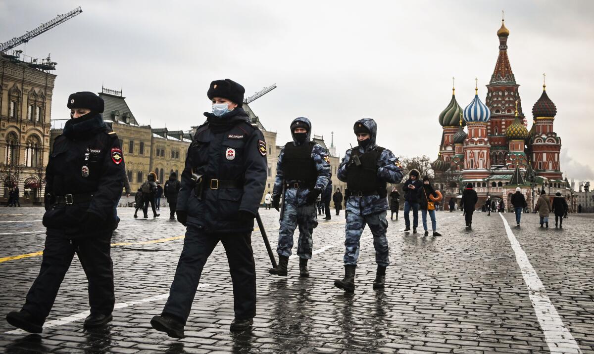 St. Basil's Cathedral is in the background as four officers  walk through a lightly populated Red Square.