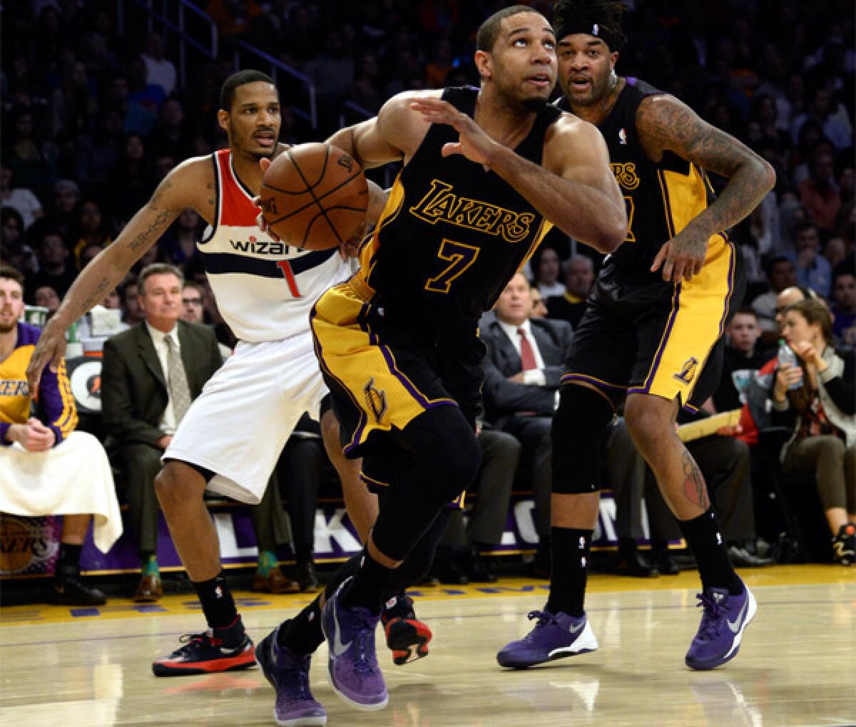 Xavier Henry gets by Washington's Trevor Ariza as Lakers teammate Jordan Hill looks on.