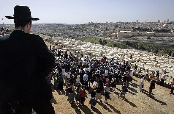 An Orthodox Jew watches as Israeli mourners carry the body of yeshiva student Segev Paniel Avihail, 15, during his funeral at Mount of Olives cemetery, which overlooks Jerusalem's Old City.
