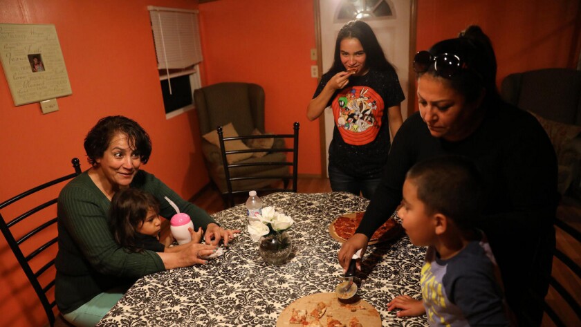 Gloria Lopez, left, holds her granddaughter Arabella, 2, at the home of her daughter Alyssa Pimentel, right, in Waukegan, Ill. Lopez and 16-year-old daughter Dayanara, center, are staying with Pimentel after leaving Puerto Rico following Hurricane Maria.