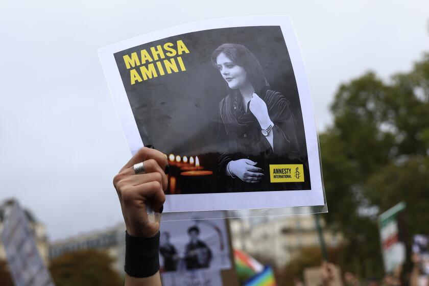 FILE - A protester shows a portrait of Mahsa Amini during a demonstration to support Iranian protesters standing up to their leadership over the death of a young woman in police custody, Sunday, Oct. 2, 2022 in Paris. Anti-government demonstrations erupted Saturday, Oct. 8, in several locations across Iran as the most sustained protests in years against a deeply entrenched theocracy entered their fourth week. The protests erupted Sept. 17, after the burial of 22-year-old Amini, a Kurdish woman who had died in the custody of Iran's feared morality police. (AP Photo/Aurelien Morissard)