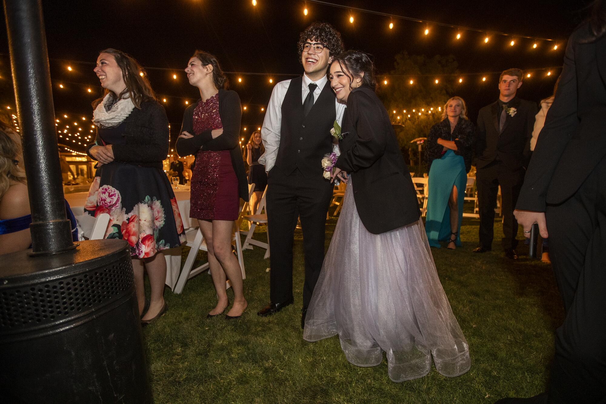 Teens stand in dresses and suits outside