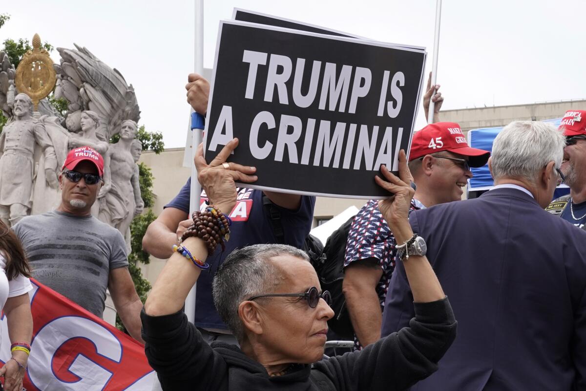 A man at a protest with a sign that reads "Trump is a criminal." 