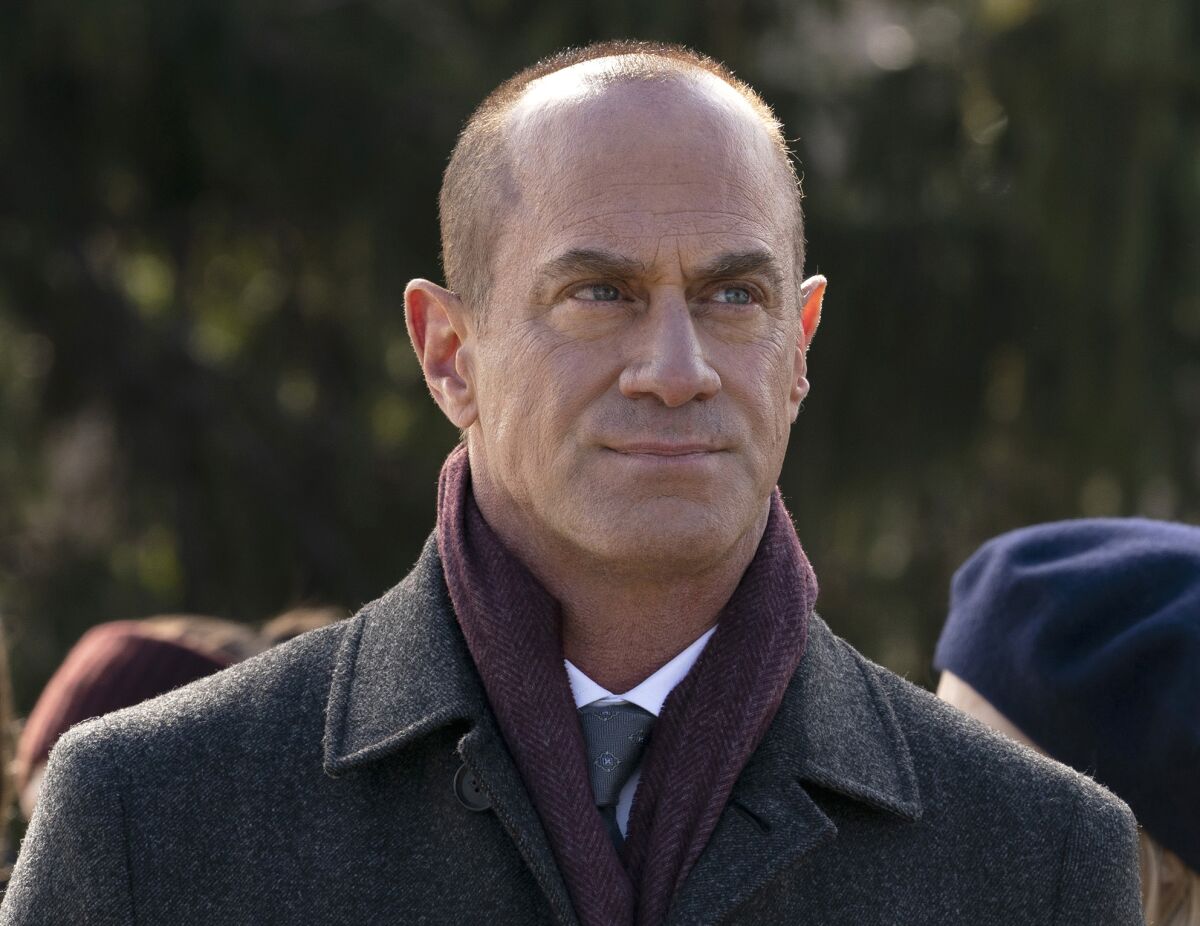 Christopher Meloni in a purple scarf and gray coat.
