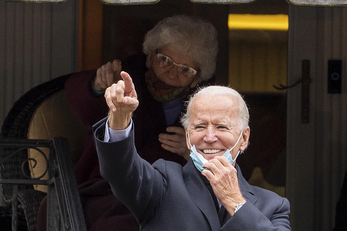 Joe Biden gestures and smiles from the front steps of his childhood home.