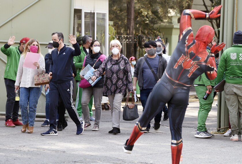 Un actor disfrazado de Spider-Man saluda a las personas que hacen fila.