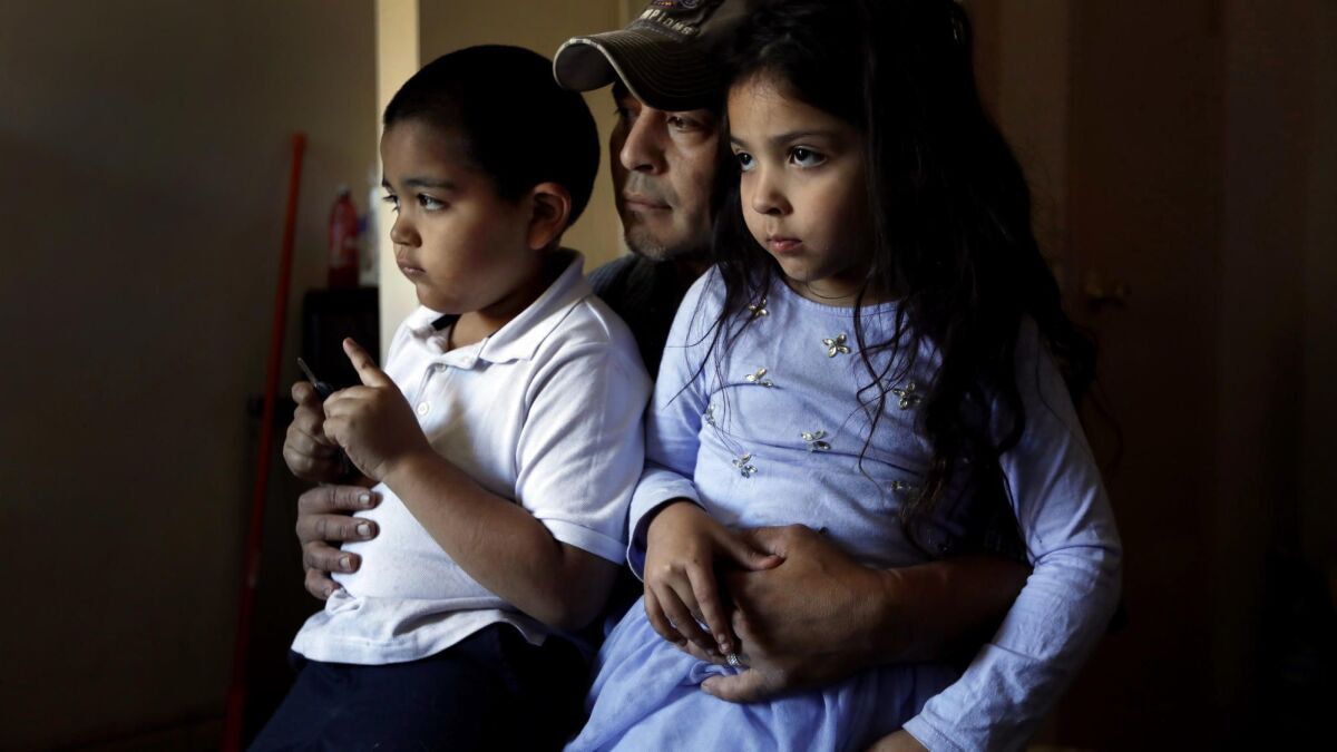 Marcos, 7, left, and Kimberly, 5, sit on their father Jose's lap at the motel in Pacoima operated by L.A. Family Housing where they've been living.