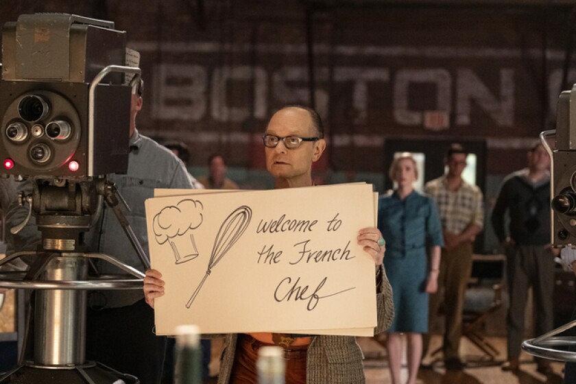 A man holds a cue card that reads "Welcome to the French Chef."