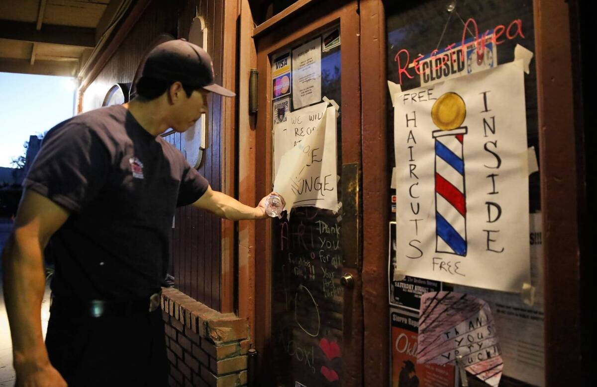 Vino Ornelas of the San Diego City Fire Department reads a note on the door of the West Side Ink tattoo parlor in Tuolumne City, Calif. The owners have re-purposed the space as a rest area, lounge and barbershop for the thouands of firefighters who are in town battling the Rim fire.