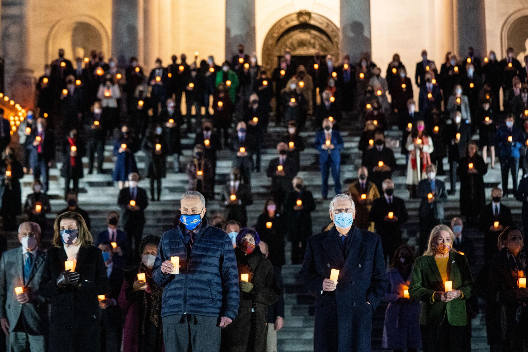 Members of the 117th Congress hold candles in a moment of silence