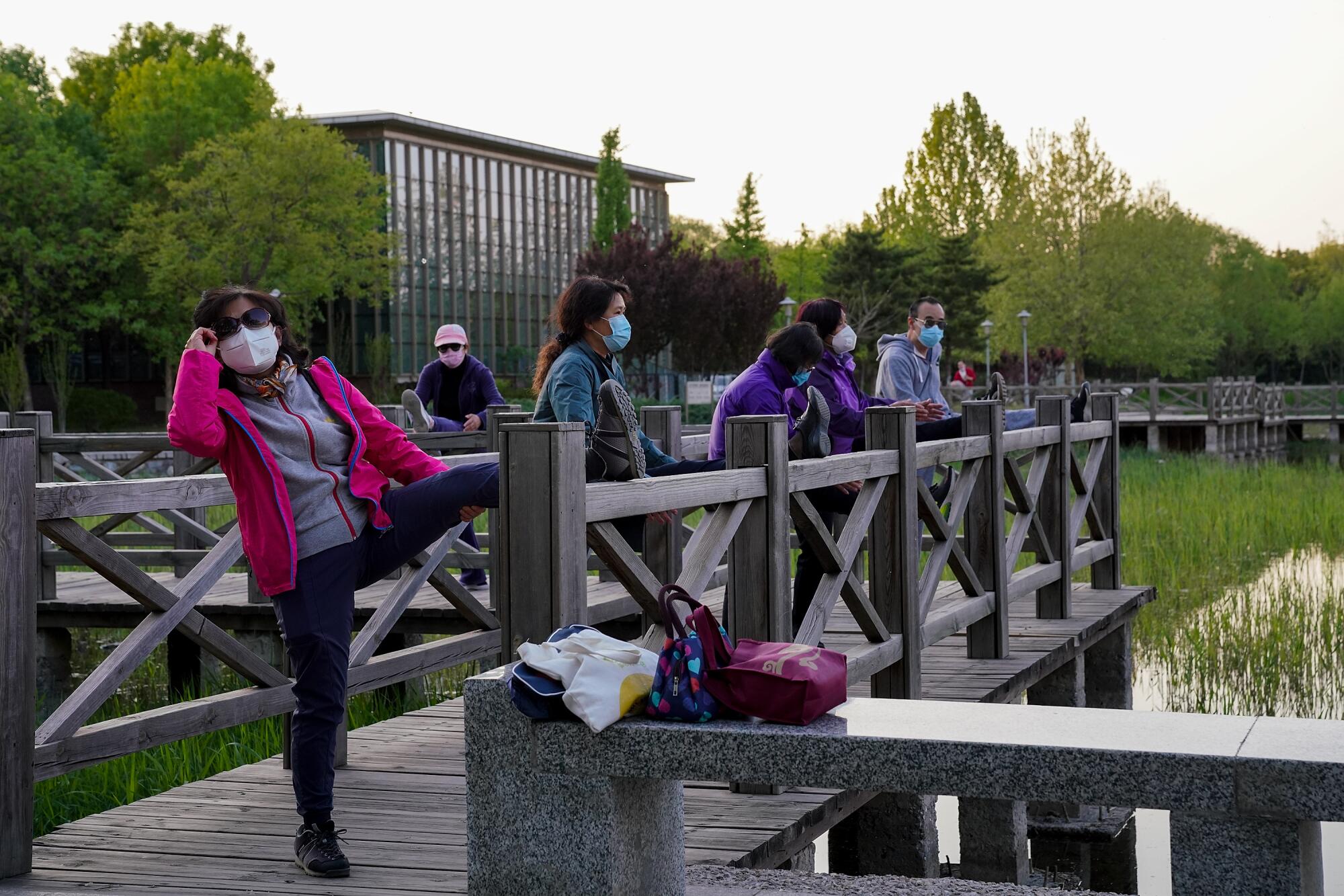Citizens wear protective masks while exercising at a park in Beijing on April 23. Life is slowly returning to normal in the capital more than three months after a lockdown was imposed to contain the coronavirus outbreak.