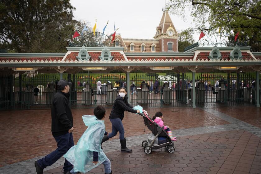 ANAHEIM, CA., MARCH 13, 2020: People walk towards the entrance of Disneyland Park on Fri., March 13, 2020 in Anaheim, CA. Disney's theme parks, Disneyland and California Adventure are closing due to precautions taken to prevent the spread of the Coronavirus. (Kent Nishimura / Los Angeles Times)