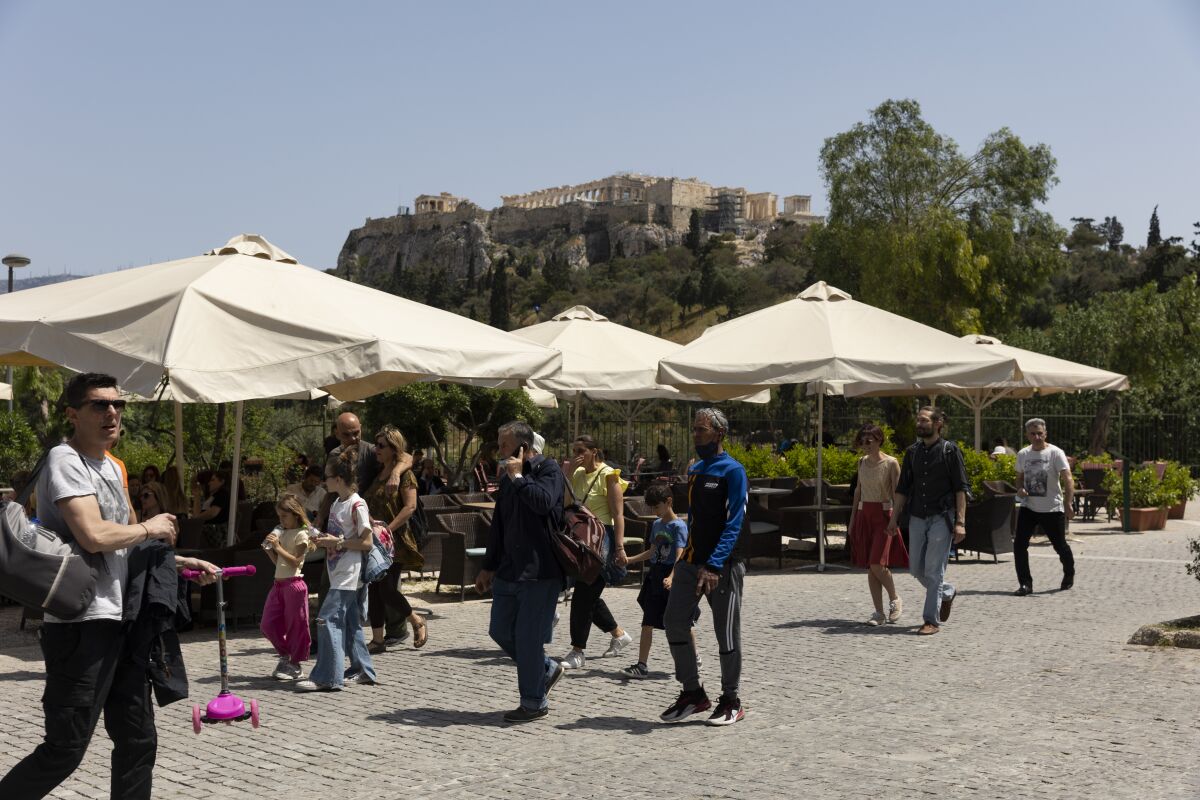 People make their way on a pedestrian street at the foot of the Acropolis hill, in Athens, on Sunday, May 1, 2022. Italy and Greece relaxed some COVID-19 restrictions on Sunday, in a sign that life was increasingly returning to normal before Europe's peak summer tourist season. (AP Photo/Yorgos Karahalis)