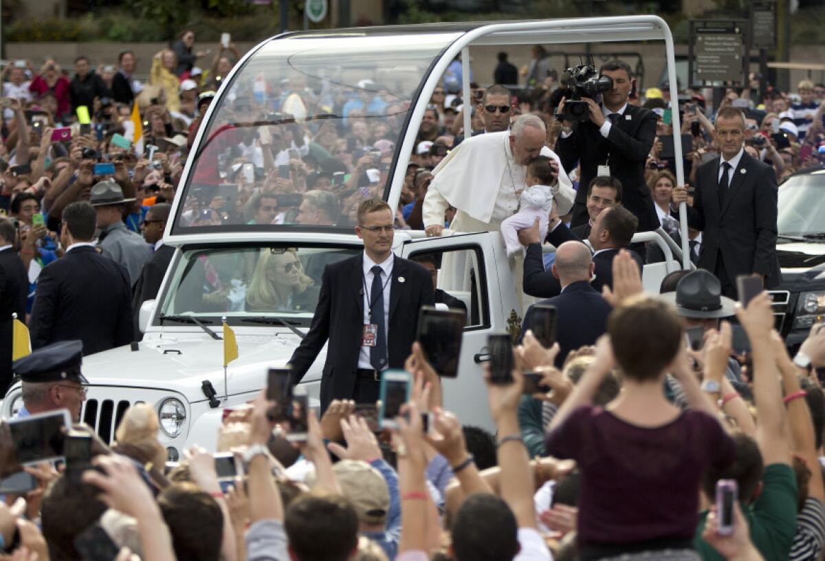 El papa Francisco besa a un bebé mientras su vehículo avanza hacia el Independence Mall antes de su discurso afuera del recinto en Filadeflia el sábado 26 de septiembre de 2015.