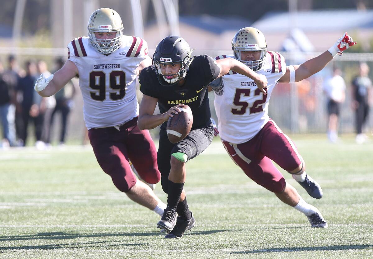 Golden West College quarterback Nathaniel Espinoza eyes the end zone as he eludes Southwestern's Brian Williams (99) and Louis Shimoum for a touchdown during a nonconference game on Saturday.