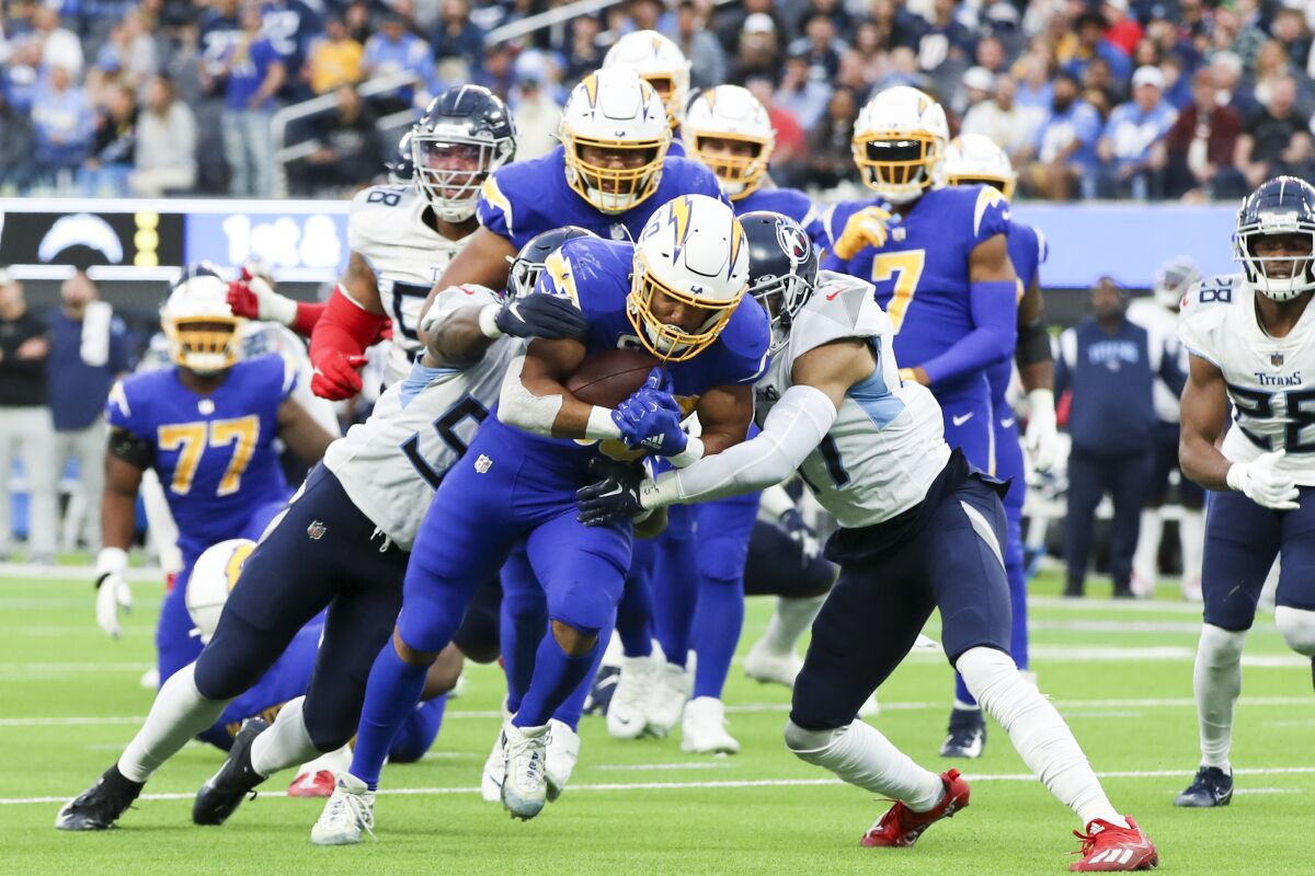 The Chargers' Austin Ekeler drags Tennessee defenders as he runs for extra yardage.