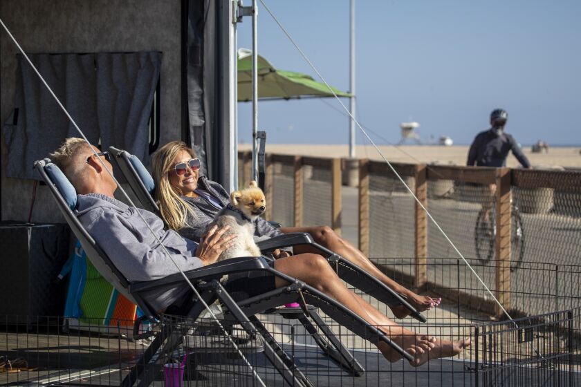 Huntington Beach, CA - September 03: Liz and Kirk Shafonsky, and their dog, Mojo, of Lake Havasu City, relax in the back of their camper as they kick off the Labor Day getaway weekend at Bolsa Chica State Beach on Friday, Sept. 3, 2021 in Huntington Beach, CA. (Allen J. Schaben / Los Angeles Times)