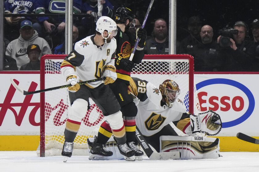 Vegas Golden Knights goalie Jonathan Quick (32) makes a glove save as teammate Alex Pietrangelo (7) and Vancouver Canucks' Phillip Di Giuseppe (34) watch during the second period of an NHL hockey game Tuesday, March 21, 2023, in Vancouver, British Columbia. (Darryl Dyck/The Canadian Press via AP)