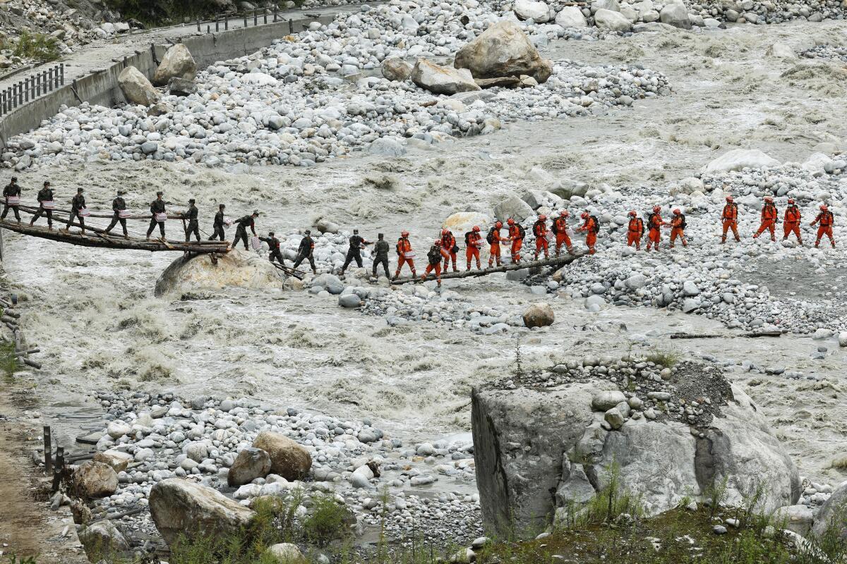 Rescuers lining a temporary bridge in the aftermath of an earthquake