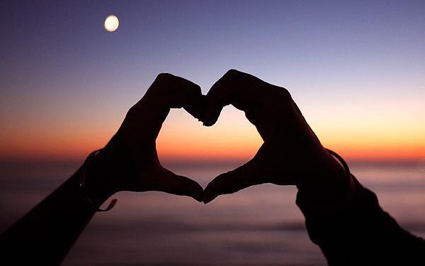 Kaitlin Schupp, 20, and Delisa Lopez, 21, both of San Diego, make the shape of a heart together with their hands while dancing to Otis Redding at Sunset Cliffs in San Diego.