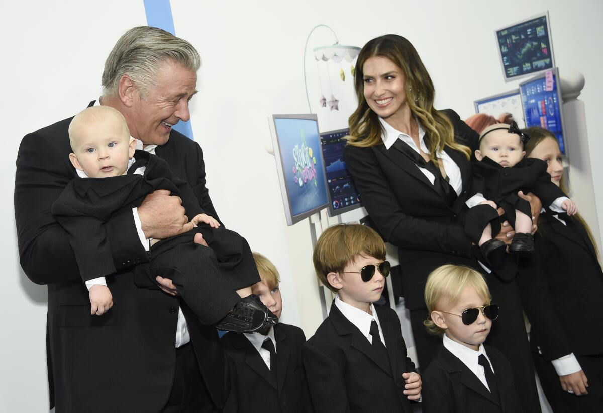 A man and a woman posing in matching black suits with several children