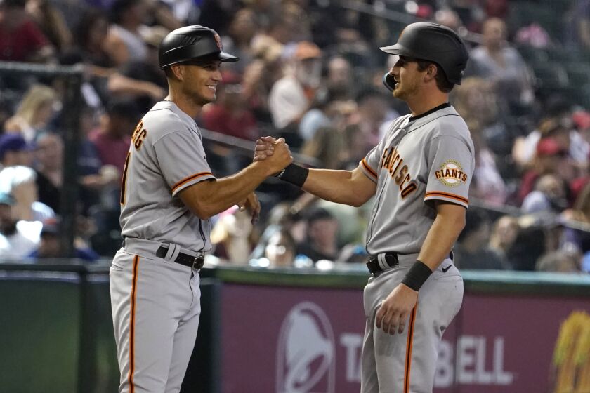 San Francisco Giants third base coach Mark Hallberg, left, congratulates Ford Proctor, right, for getting his first hit in the major leagues in the seventh inning of a baseball game against the Arizona Diamondbacks Sunday Sept. 25, 2022, in Phoenix. (AP Photo/Darryl Webb)
